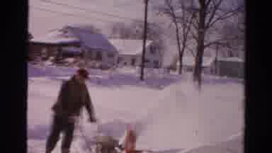 Toledo Ohio USA (1954): Man Wearing Black Hat Follows Man Pushing Snowblower On A