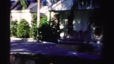 Dade County Florida (1955): Woman Wearing Tan Shorts Walks Toward White Building