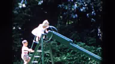 Hicksville New York (1955): Two Kids Playing On A Green Slide Being Watched By A