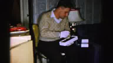Albany New York (1955): A Man Wearing Gloves Eats Piece Of Chocolate And Offers