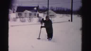Albany New York (1955): Man Wearing Black Coat Begins Shoveling Snow From Fence On