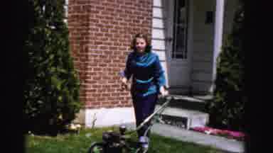 Albany New York (1955): Woman Attempts To Start An Old Lawn Mower Outside Home