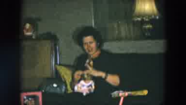 Hicksville New York (1956): Woman Wearing Brown Dress Sits On Sofa Combine Toy