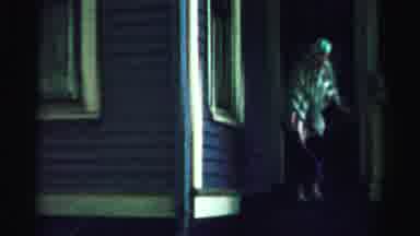 NORMAL ILLINOIS USA-1957: Elder Woman Cleans Front Steps With Hose At Night