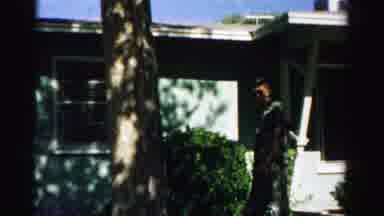 Normal Illinois USA (1957): Men Walking In Front Of House Puts Hands On Hips Woman