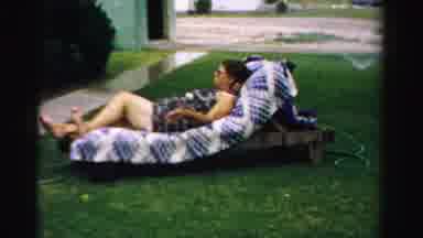 Normal Illinois USA (1957): A Woman Reclines In Lawn Furniture On The Lawn Of A