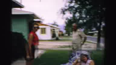 Normal Illinois USA-1957: Woman in Red Shirt, Man, and Dog in Suburban Yard