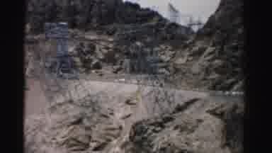 Nevada USA (1957): Man And Woman Walk Near A Car While A Truck Drives On A Hill In