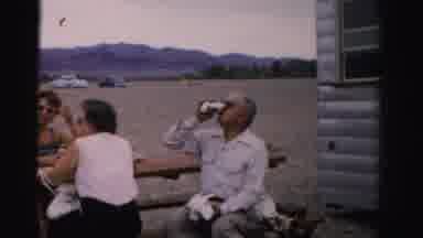 Nevada USA (1957): Three People Sitting At A Picnic Table Watching Kids In A Lake