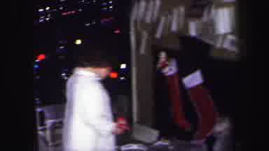 Lynbrook New York (1971): Woman Wearing Black Dress Opens Gift While Kids Play