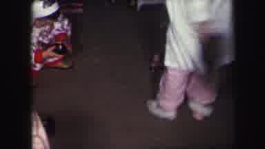 Lynbrook New York (1971): Man Wearing White Shirt Sets Baby Wearing Red Pants Next