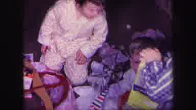 Lynbrook New York (1971): Three Children Wearing Pajamas Unwrapping Christmas