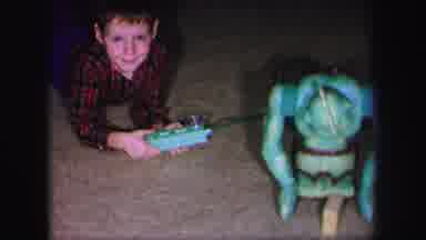Lynbrook New York (1971): Boy Wearing Red Plaid Shirt Plays With Turquoise Robot