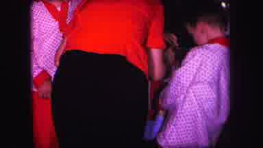 Lynbrook New York (1971): Woman Wearing Red Shirt Helps Baby Wearing Blue Pajamas