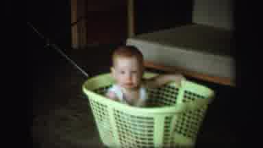 Lynbrook New York (1971): Baby Wearing White Shirt Sits In Green Laundry Basket