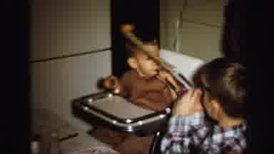 Lynbrook New York (1971): Baby Wearing Brown Shirt Sits In Highchair Blowing On