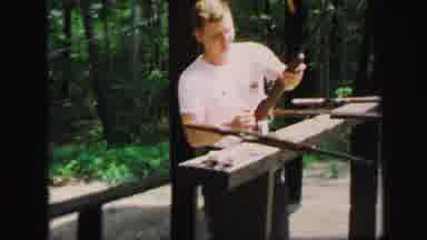 Lynbrook New York (1971): A Man Standing In Front Of Several Rifles As He Lifts