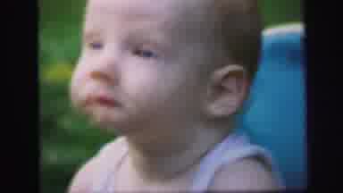 Lynbrook New York (1971): Baby Sits In Blue Walker On Green Grass Looking Around