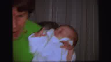 Lynbrook New York (1971): Woman Wearing Green Shirt Holds Baby Wearing White Shirt