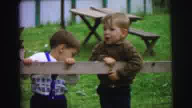 Lynbrook New York (1973): Two Boys Hang Over Wooden Fence While Girl Wearing