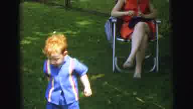 Lynbrook New York (1973): Woman Wearing Red Dress Sits In Chair While Children