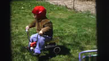 Lynbrook New York (1973): Small Child Pushes Self Along On Tricycle Another Child