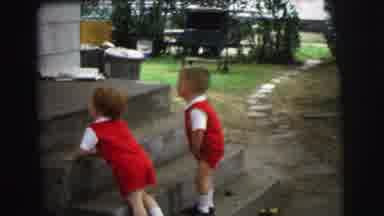 Lynbrook New York (1973): Twin Boys Wearing Red Shorts Stand Next To Concrete