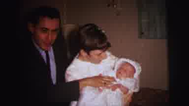 Lynbrook New York (1973): Man And Woman Holding Fussy Baby Wearing White Baptismal
