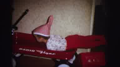 Lynbrook New York (1973): Boy Wearing Red Pajamas Climbs Into Red Wagon Next To
