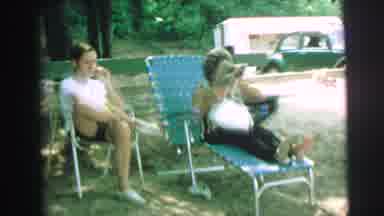 Lynbrook New York (1973): People Sitting In Lawn Chairs Next To Green Fence On A