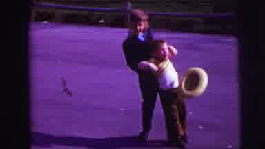 Lynbrook New York (1973): Boy Wearing Black Suit Swings Boy With Cowboy Hat In A
