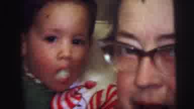 Lynbrook New York (1973): Toddler Wearing Green And White Bib Eats While Woman