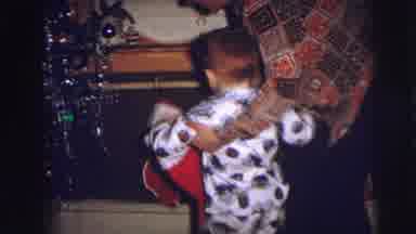 Lynbrook New York-1973: Boy Wearing White Pajamas Reaches for Christmas Stocking Near Tree