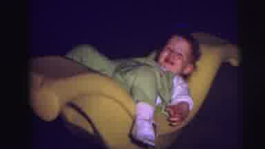 Lynbrook New York (1973): Baby Laughs And Smiles As Mother Rocks Baby In Yellow