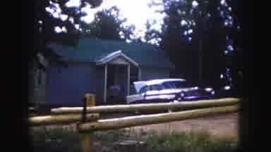 Colorado Springs USA (1958): Woman Wearing Pink Dress Walks Into Grey House On A