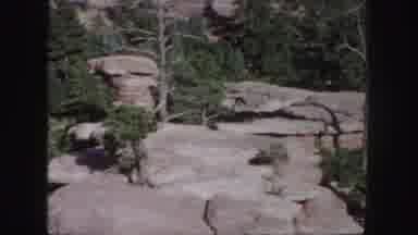 Colorado (1958): A Picturesque View Of A Rocky Landscape Covered In Green Foliage
