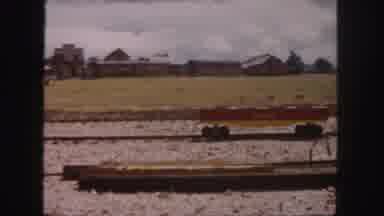 Colorado (1958): Man Walking Away From Brown Building On A Sunny Day