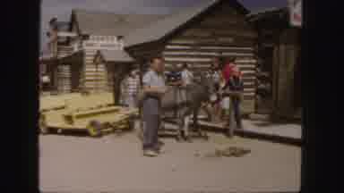 Colorado (1958): People Walking Down A Sidewalk Passed A Donkey In A Old West