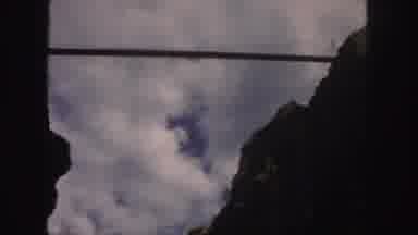COLORADO-1958: Dark Mountain Peaks Framing Blue Sky Peeking Through White Puffy Clouds