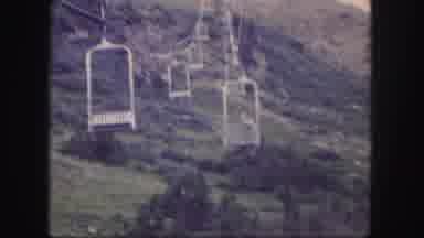 Colorado USA (1958): A Man Traveling On A Ski Lift Up A Mountain That Is Green And