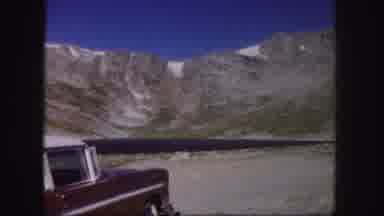Colorado USA (1958): Old Style Red Car Parked By A Lake Surrounded By Sheer Cliff