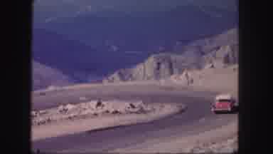 Colorado USA (1958): Red Car Driving Around Road Curve Overlooking Brown Mountains