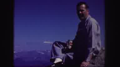 Colorado USA (1958): Man Wearing Blue Shirt Sits On Rock With Beverage On A Sunny