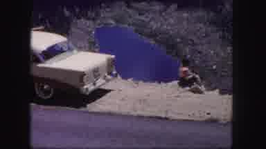 Colorado USA (1958): A Woman Sitting Near A Parked Car And Road Overlooking A