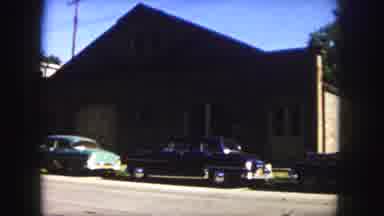 Denver Colorado (1958): A Dark Colored Vintage Car Is Parked In Front Of A