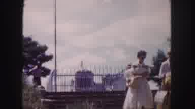 Denver Colorado (1958): People Walking Away From A Monument That Is Protected By A