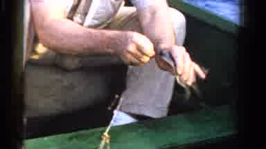 Ontario Canada (1958): Man In A Boat Removing Hook From A Fish