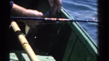 Ontario Canada-1958: Man With Wedding Ring On Boat Detaches Caught Fish From
