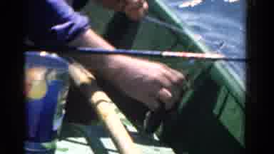 Ontario Canada (1958): Man In Small Boat Holds Up Fish He Just Caught With Rod To