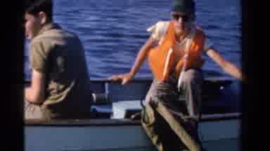 Ontario Canada (1958): Man Wearing White Shirt Looks At People Riding In Motorboat